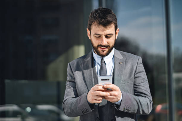 istock Handsome confident businessman text messaging on a mobile phone 1215688395