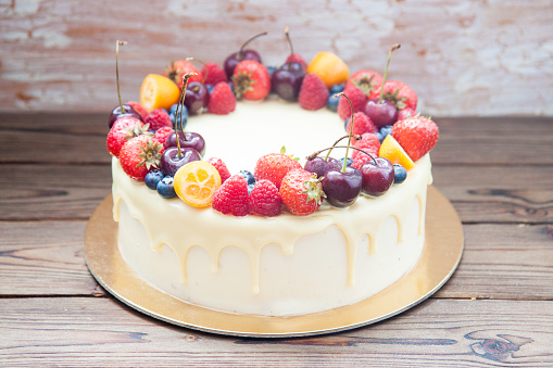 Cheesecake with white chocolate, fresh berries, strawberries, cherries, blueberries and raspberries on wooden background. Summer dessert.