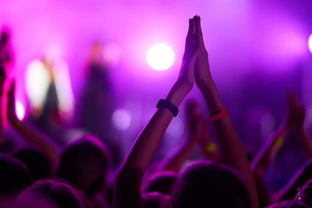 Cheering crowd at a rock concert. Music fans enjoying rock concert with hand in the air.  Crowd raising their hands, dancing and enjoying great the concert.