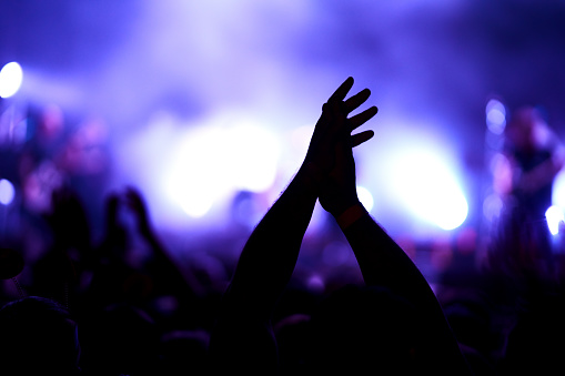 Cheering crowd at a rock concert. Music fans enjoying rock concert with hand in the air.  Crowd raising their hands, dancing and enjoying great the concert.