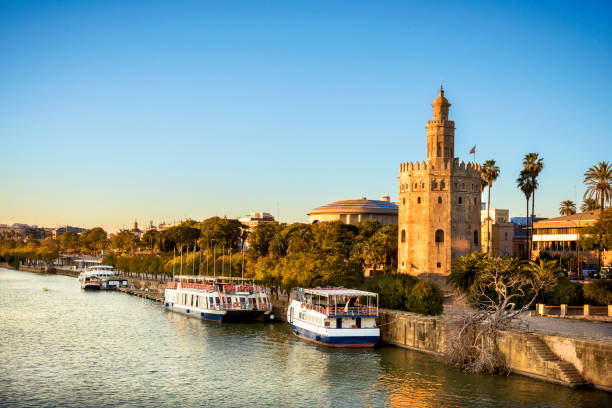 view of golden tower (torre del oro) of seville, andalusia, spain over river guadalquivir at sunset - seville sevilla torre del oro tower imagens e fotografias de stock