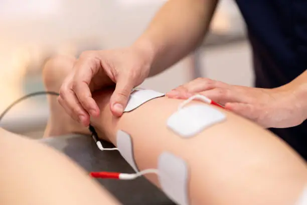 Physiotherapist applying electro stimulation in physical therapy to a young woman.