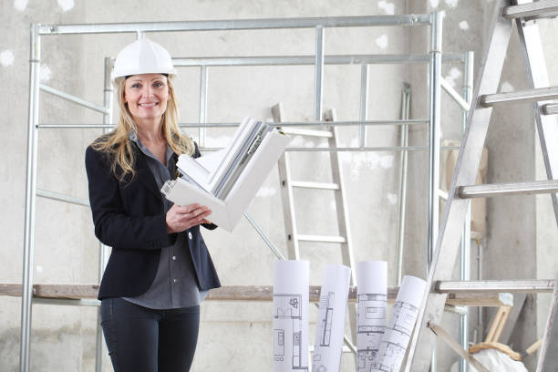 istock smiling woman architect or construction interior designer with white windows cutaway profile inside a building site with ladder and scaffolding in the background 1215696599
