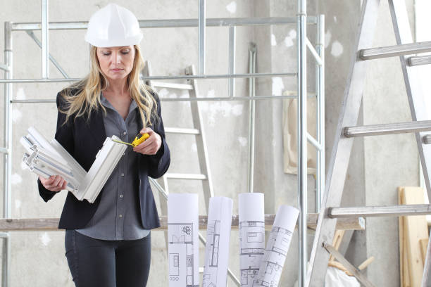 istock woman architect or construction interior designer with with meter measuring white windows cutaway profile inside a building site with ladder and scaffolding in the background 1215696617