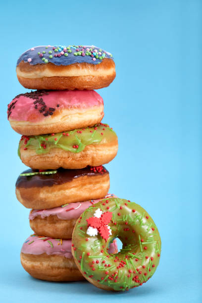 istock A stack of sweet donuts on a blue background. Concept desserts, different colored donuts laid out on top of each other by a tower. Copy space, blue background 1215696750