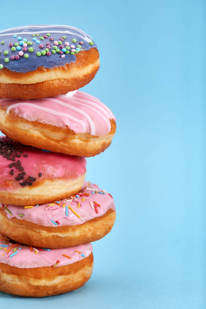 istock A stack of sweet donuts on a blue background. Concept desserts, different colored donuts laid out on top of each other by a tower. Copy space, blue background 1215696854