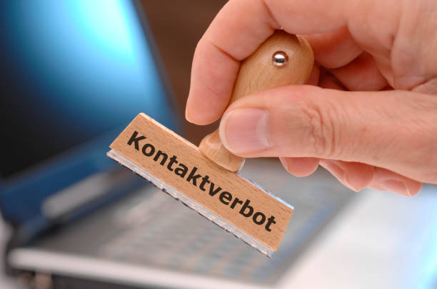 istock rubber stamp in hand with curfew (german: Kontaktverbot) printed on it 1215696861