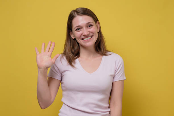istock Attractive friendly looking young woman smiling happily, saying Hello, Hi or Bye 1215698552