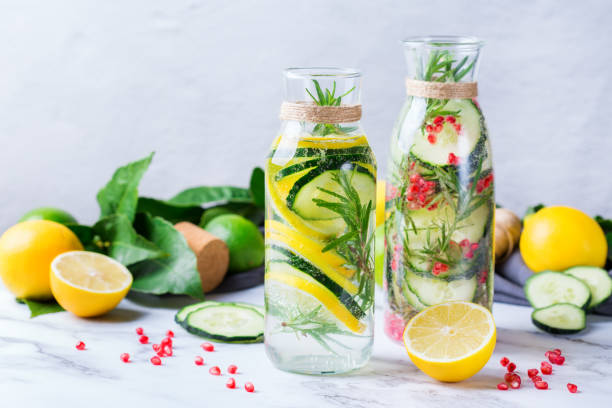 Fresh cool lemon cucumber rosemary infused water detox drink Health care, fitness, healthy nutrition diet concept. Fresh cool lemon cucumber rosemary pomegranate infused water, detox drink, lemonade in a glass jar for spring summer days. infused water stock pictures, royalty-free photos & images