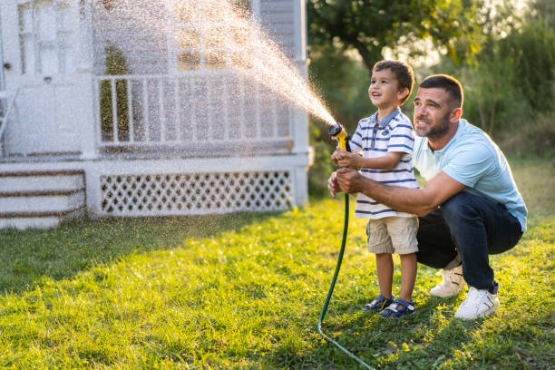 istock Father splashing water and having fun with son on back yard 1215700680
