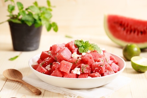 watermelon salad with feta cheese and mint leaves in white bowl on wooden table