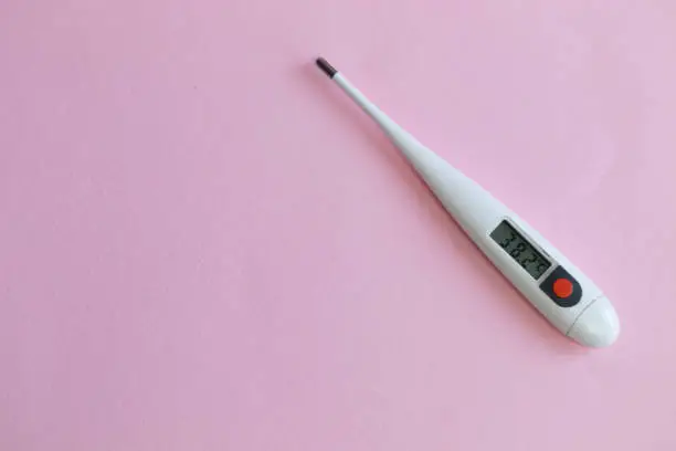 Photo of Thermometer with a high temperature lies on a pink background