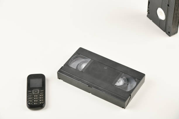 istock Retro objects on a white background. push-button telephone and video cassette. Analog media technology of the past. Copy space 1215702280