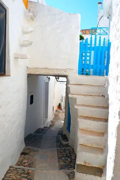 Photo of One of the charms of Mykonos, Greek island in the heart of the cyclades, are its narrow streets : white houses with small flowered balconies touching almost above paved streets