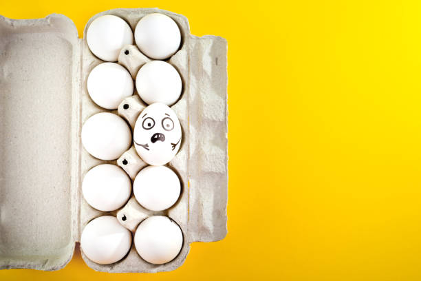 istock Easter egg with funny face in tray on yellow background. 1215704490