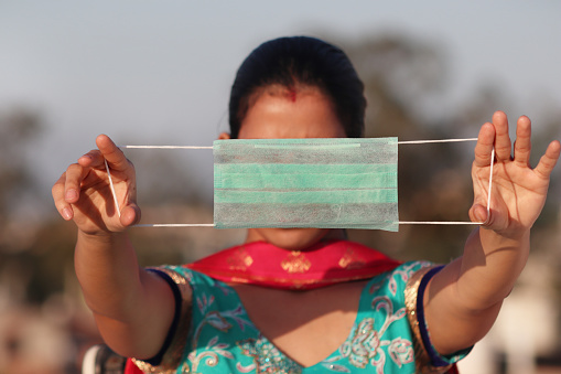 Young women of Indian ethnicity holding protective face mask in hand. Medical mask and corona virus protection masks.