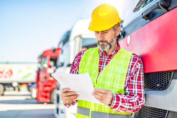 istock Truck driver delivering a load and checking paperwork. 1215705405