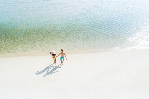 Couple walking into seawater at the beach - bird eye view