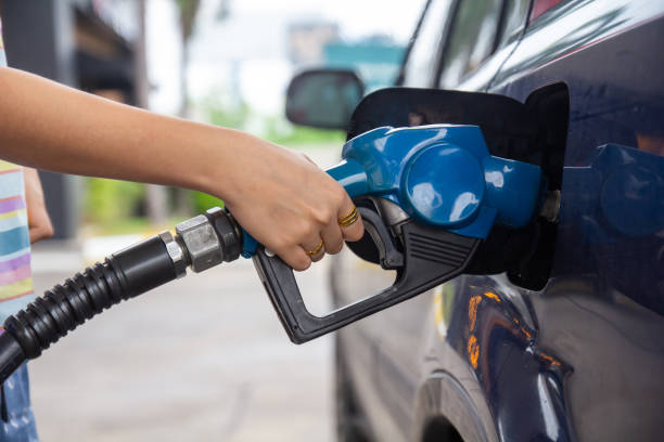 синий автомобиль на заправке, наполненный топливом. крупным планом женщина стороны перекачки бензинового топлива в автомобиле на азс. - gasohol стоковые фото и изображения
