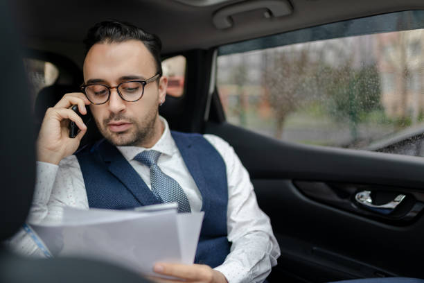 istock Confident Turkish businessman reading document while talking on smart phone in car. 1215709038
