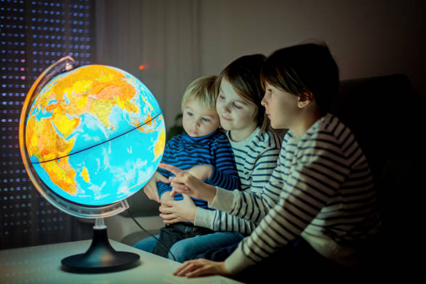 istock Little children, brothers, looking at illuminated globe, exploring 1215709111