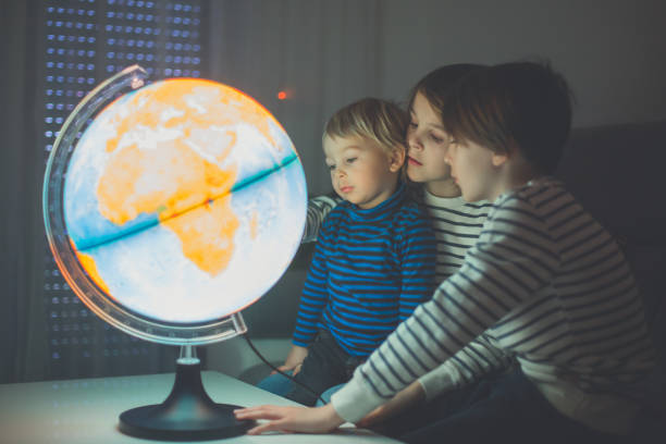 istock Little children, brothers, looking at illuminated globe, exploring 1215709125
