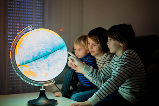 istock Little children, brothers, looking at illuminated globe, exploring 1215709154