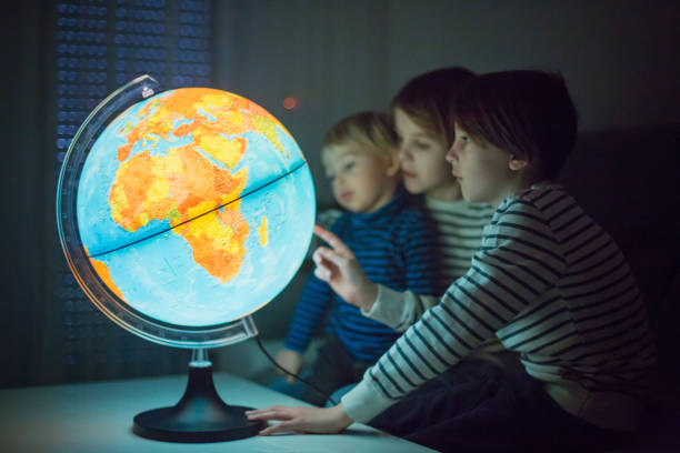 istock Little children, brothers, looking at illuminated globe, exploring 1215709188