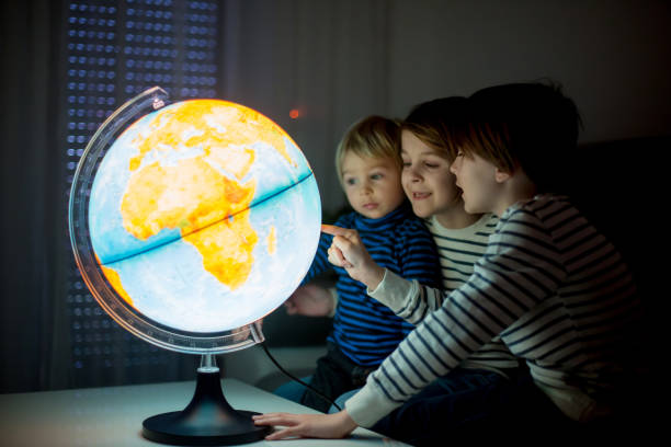 istock Little children, brothers, looking at illuminated globe, exploring 1215709212