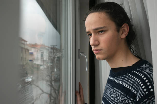 Young man watching empty street in anxiety from his home stock photo