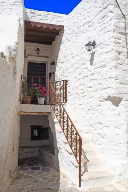 Photo of One of the charms of Mykonos, Greek island in the heart of the cyclades, are its narrow streets : white houses with small flowered balconies touching almost above paved streets