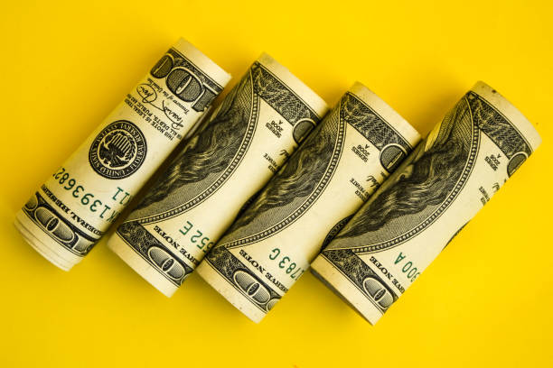 istock American dollars in rolls. Saving money concept on yellow background with copy space for text 1215709940