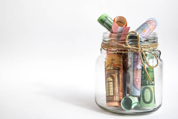 istock Glass jar with euro notes isolated on white background, euros rolled up 1215711420