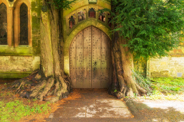 An old English village church door with yew trees at St Edward's Church, Stow-on-the-Wold, England.