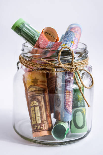 istock Glass jar with euro notes isolated on white background, euros rolled up 1215711794