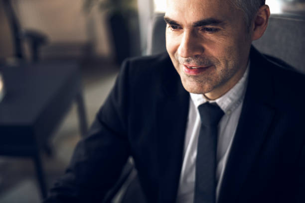 istock Mature smiling office worker in suit working at computer 1215711828