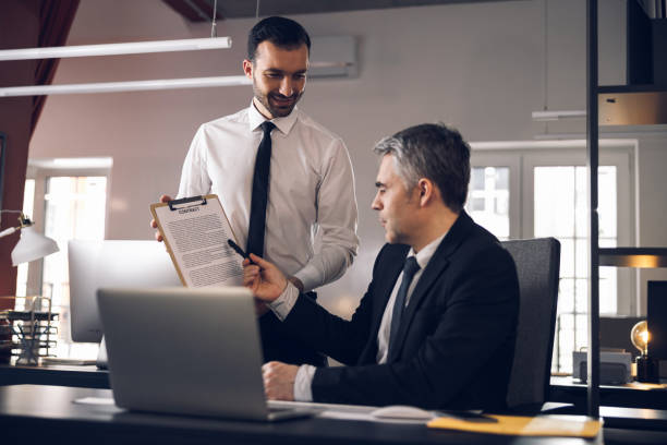 istock Mature boss in suit signing papers in office 1215711837