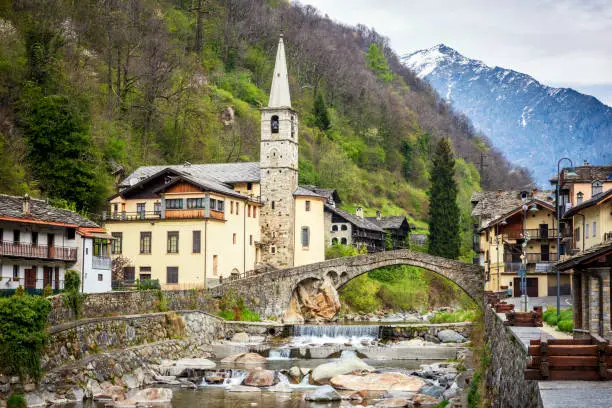 Photo of Fontainemore alpine village on the Lys river in a forest in the valley of Gressoney near Monte Rosa during spring. Aosta Valley, Aosta, Italy.