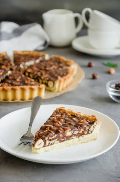 istock Tart with chocolate caramel, hazelnuts, peanuts, almonds and seed mix on a dark concrete background. Vertical orientation. 1215713567