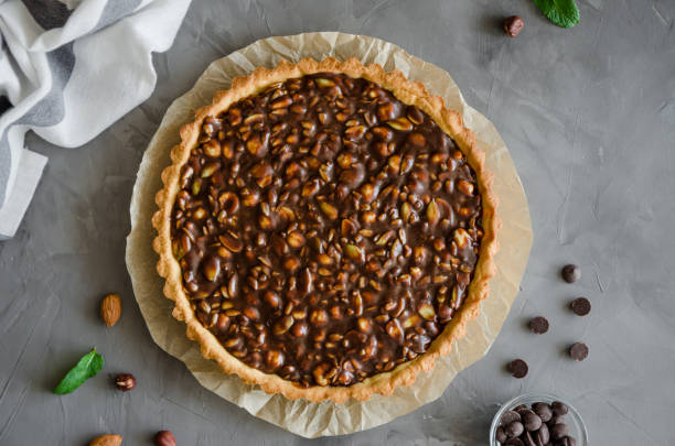 istock Tart with chocolate caramel, hazelnuts, peanuts, almonds and seed mix on a dark concrete background. Horizontal orientation. Top view. 1215713570