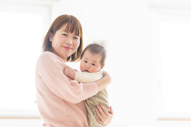 istock Mom holding a baby in a bright room 1215718862