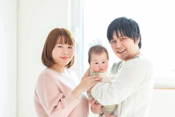 istock Dad and mom holding a baby in a bright room 1215718942