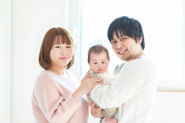 istock Dad and mom holding a baby in a bright room 1215718947