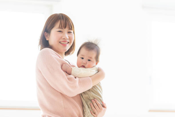 istock Mom holding a baby in a bright room 1215718974