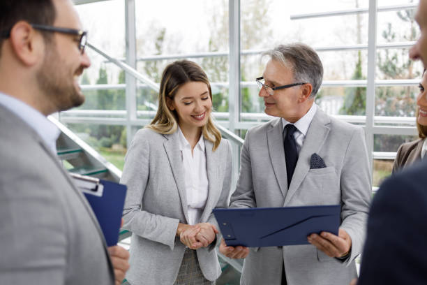 istock Mixed age range business people standing in a lobby and consulting 1215723341