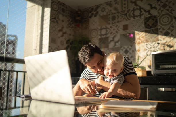 Man holding his son and working with laptop at home