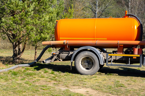 Sewer tank truck providing cleaning service outdoor. Specialised car, sewage pumping machine