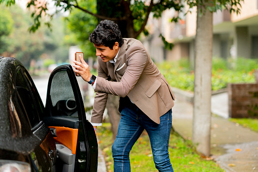 The Uber user in Bogota Colombia shows his cell phone to the driver when he comes to pick him up from the street while a heavy rain falls