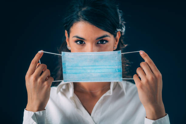 istock Coronavirus Disease Prevention. Beautiful Young Woman Putting Protective Mask On 1215724836