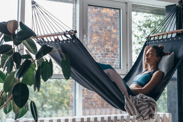 istock Woman is lying at home in a hammock and resting 1215725037